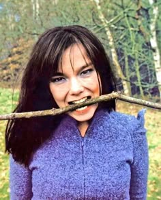 a woman holding a branch over her mouth