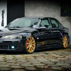 a black car with gold rims parked in front of a building