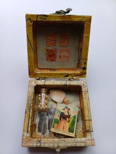 an old wooden box with some pictures in it's lid and contents inside that are missing