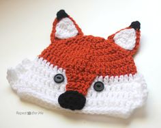 a crocheted hat with a fox's head on it is laying down