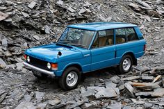 a blue jeep parked on top of a pile of rocks