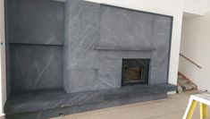 a fireplace in the middle of a room being built with gray marble and steel paint