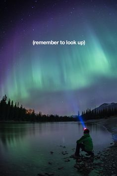 a man sitting on the edge of a lake under an aurora bore with text that reads, where to see the northern lights