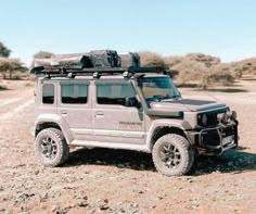 a grey jeep parked on top of a dirt field