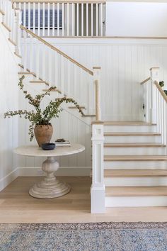 there is a vase with flowers sitting on the table in front of the stair case