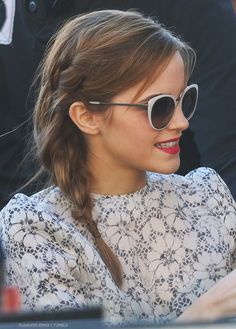 a woman wearing sunglasses looking at her cell phone while sitting in front of other people