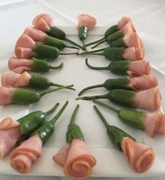 a white plate topped with green beans and ham wrapped in rolled up flowers on top of it