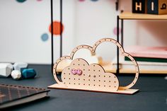 a wooden cloud with two pink hearts on it sitting next to a notebook and pen