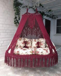 a red hammock hanging from a brick wall with pillows on the bottom and side