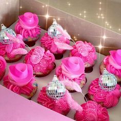 cupcakes with pink frosting and decorations in a box