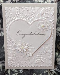 a white card with flowers and hearts on it, which says congratulations in the center