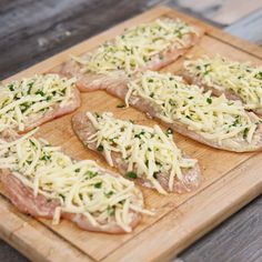 several pieces of meat covered in cheese on a cutting board