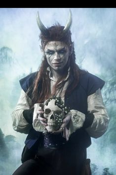 a man with horns holding a skull in his hands