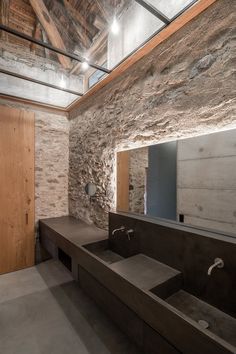 a bathroom with stone walls and flooring is shown in this image, there are two sinks on either side of the bathtub