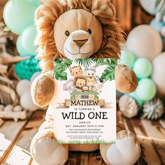 a stuffed animal holding a sign with the words, wild one on it and balloons in the background