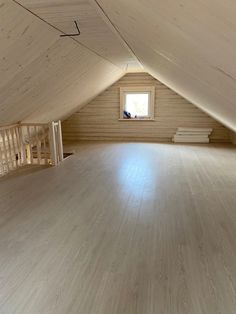 an empty attic with wood floors and white walls