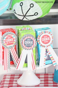 three cookie award ribbons sitting on top of a table next to boxes and paper plates