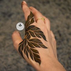 a woman's hand with a leaf tattoo on it