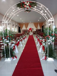 the aisle is decorated with red and white flowers, greenery, and ribbons for an elegant wedding ceremony