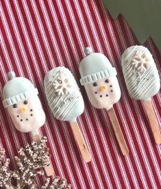 four marshmallows with frosting and snowmen on them