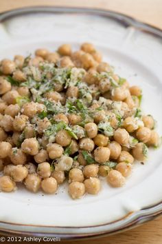 a white plate topped with chickpeas covered in parmesan cheese and herbs