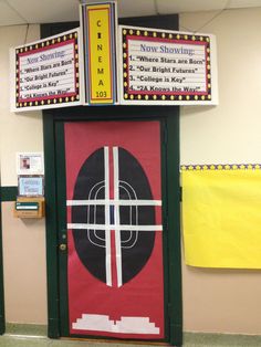 a classroom door decorated with an arrow and cross on the top, next to a bulletin board