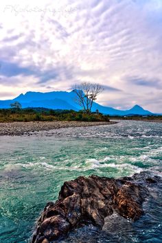 an island in the middle of some water with mountains in the backgrouds