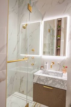 a bathroom with marble counter tops and gold accents on the mirror above the sink, along with a walk in shower