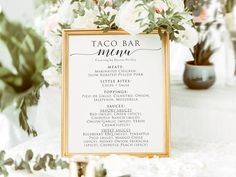 a table with a sign that says taco bar menu and flowers in vases