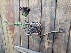 a flower that is attached to the side of a wooden door with an iron handle