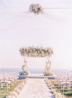 an outdoor ceremony setup with white flowers and greenery on the aisle, overlooking the ocean