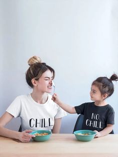 two women sitting at a table with bowls of food