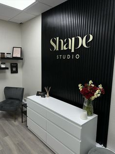 a white dresser sitting in front of a black wall with a sign that says shape studio