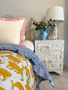 a bed room with a neatly made bed next to a night stand and two vases