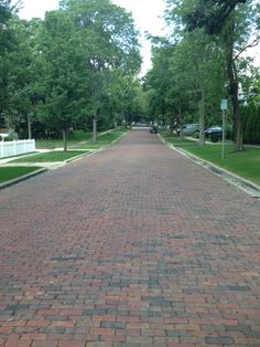 an empty brick road in the middle of a park