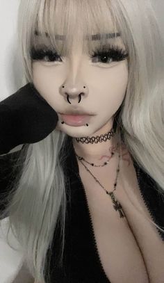 a woman with long white hair and piercings on her nose is posing for the camera