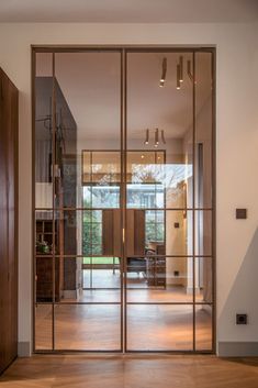 an open glass door leading to a living room with wood floors and furniture in the background