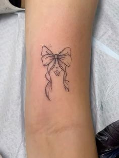 a woman's arm with a small bow tattoo on the left side of her leg