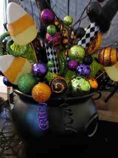 a vase filled with lots of different colored candies on top of a black table