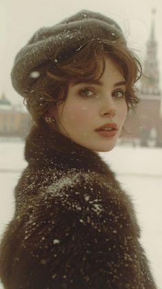 a woman wearing a fur coat and hat in the snow