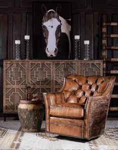 a brown leather chair sitting in front of a horse head on a wall next to a table