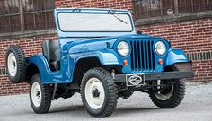 an old blue jeep parked in front of a brick building