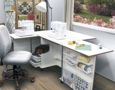 a computer desk with a chair next to it and sewing supplies on the shelf below