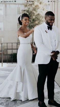 a man and woman standing next to each other in front of a building with columns