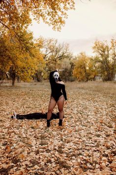 a person in a mask and bodysuit is laying on the ground surrounded by leaves