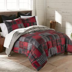 a bed with red and black plaid comforter on it in a room next to a window