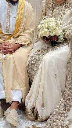 two people sitting next to each other in wedding outfits