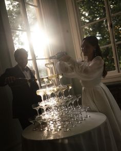 a man and woman standing next to a table filled with wine glasses