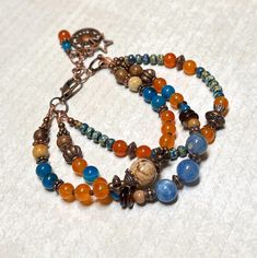 Beautiful and colorful boho bracelet with a bit of a rustic vibe.  For this bracelet I have used three different sizes of blue Agate gemstone beads, orange dyed Quartzite stones, wood beads, aged Japanese Picasso seed beads, antique copper accents, and a Zebra Jade stone bead as a focal.  Bracelet closes with a lobster clasp, and has an extender chain finished with a copper sun charm, a copper star charm, and a small bead dangle.   Bracelet best fits a wrist size between 6-1/2" - 7-1/4".   If a longer extender is needed, please leave a note at checkout. Thank you for shopping with The Lucie Collection! Rustic Multicolor Beaded Bracelets As Gift, Rustic Adjustable Multicolor Beaded Bracelets, Adjustable Agate Beaded Bracelets In Bohemian Style, Rustic Multicolor Round Bead Bracelets, Rustic Style Multicolor Beaded Bracelets, Bohemian Bracelets With Natural Stones And Agate, Multicolor Rustic Beaded Bracelets, Bohemian Agate Beaded Bracelets With Round Beads, Bohemian Agate Bracelets With Colorful Beads