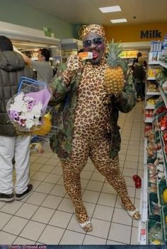 a man in a costume holding a pineapple and wearing sunglasses while standing in a grocery store